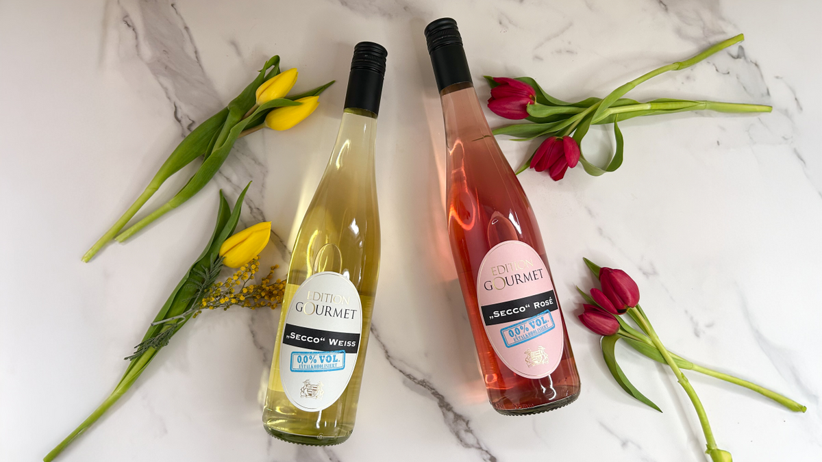 Edition Gourmet Secco Weiss und Rosé alkoholfrei liegen zwischen Tulpen auf Marmor