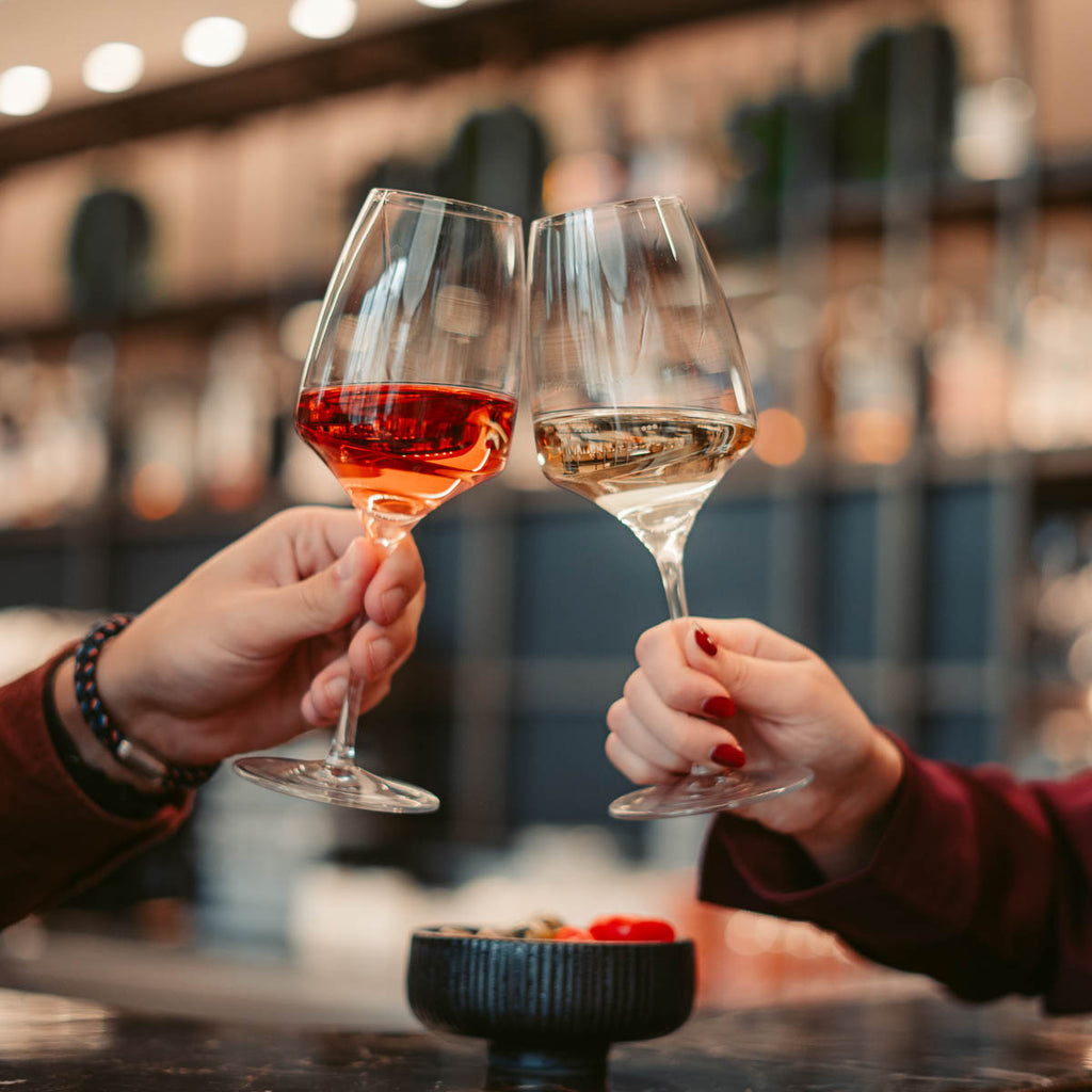 Zwei Personen stoßen mit Wein aus dem Sortiment der WZG in geselliger Runde an.