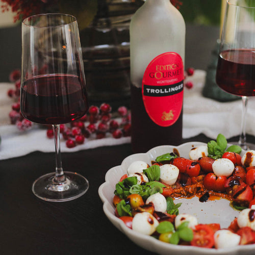 Winterlicher Tomaten-Mozzarella Salat mit einer Flasche Edition Gourmet und gefüllten Rotweingläsern