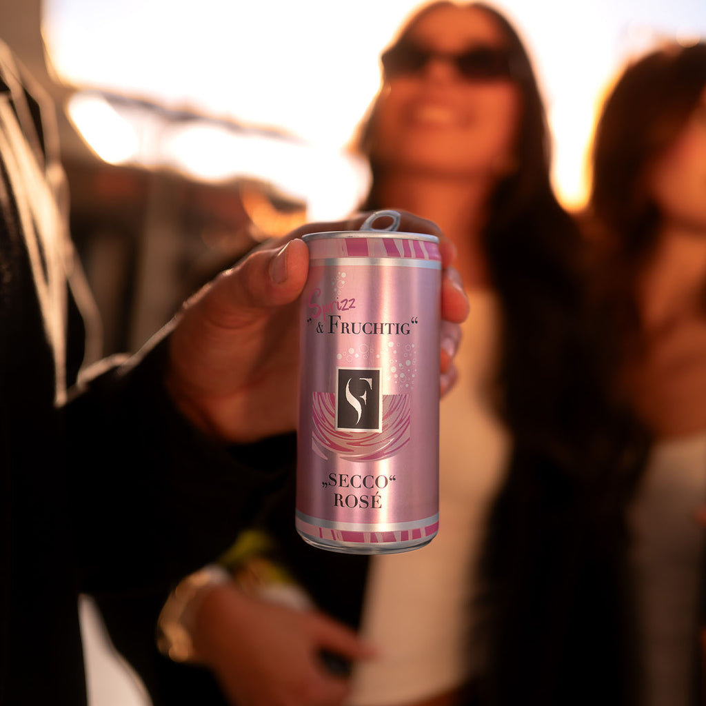 Frau mit Sonnenbrille mit Freunden halten eine Sprizz & Fruchtig Secco Rose Dose der WZG in der Hand. 