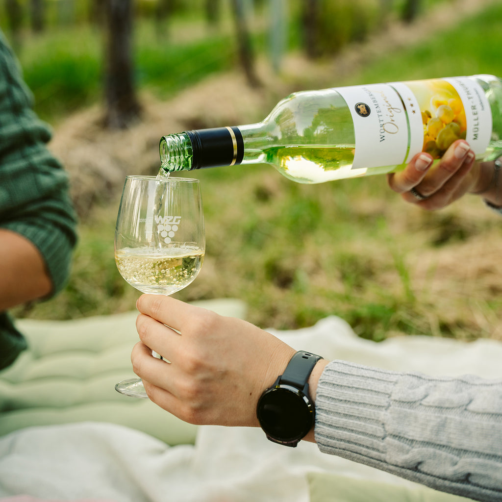Weißwein aus dem Sortiment der WZG wird im Grünen in ein Weinglas eingeschenkt.