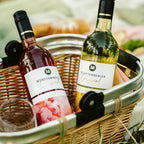 Roséwein und Weißwein aus dem Sortiment der WZG in einem Picknickkorb mit Gläsern und Snacks.
