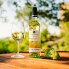 Flasche Weißwein Württemberger Original Müller-Thurgau der WZG mit gefülltem Weinglas auf einem Holztisch in sommerlicher Gartenatmosphäre.