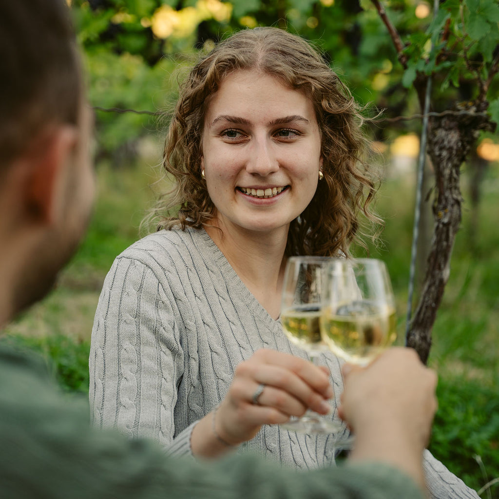 Paar stößt mit Weißwein in einem Weinberg an