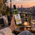 Württemberger Original Riesling von WZG wird bei Sonnenuntergang auf einer Terrasse mit Blick über die Stadt in der Hand gehalten.